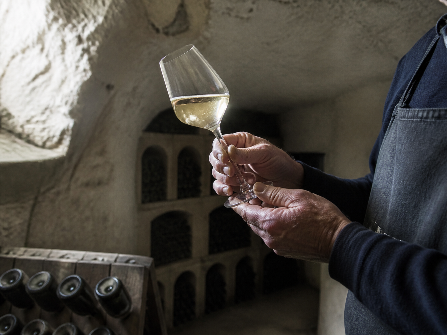Champagnemaker beoordeelt een cuvée in een traditionele kalkkelder