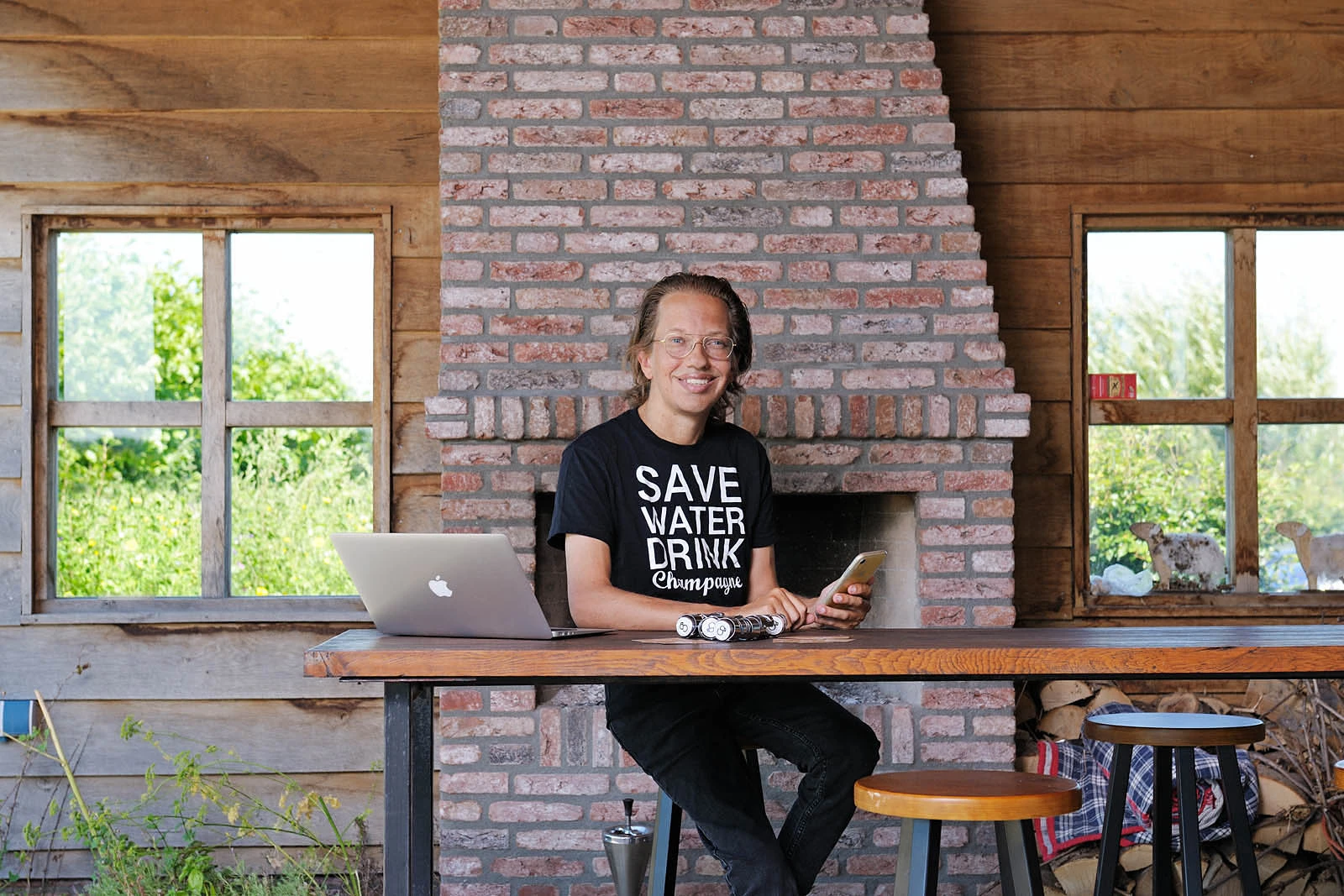 igenaar van Champagne Baron in rustieke setting met laptop en champagnefles